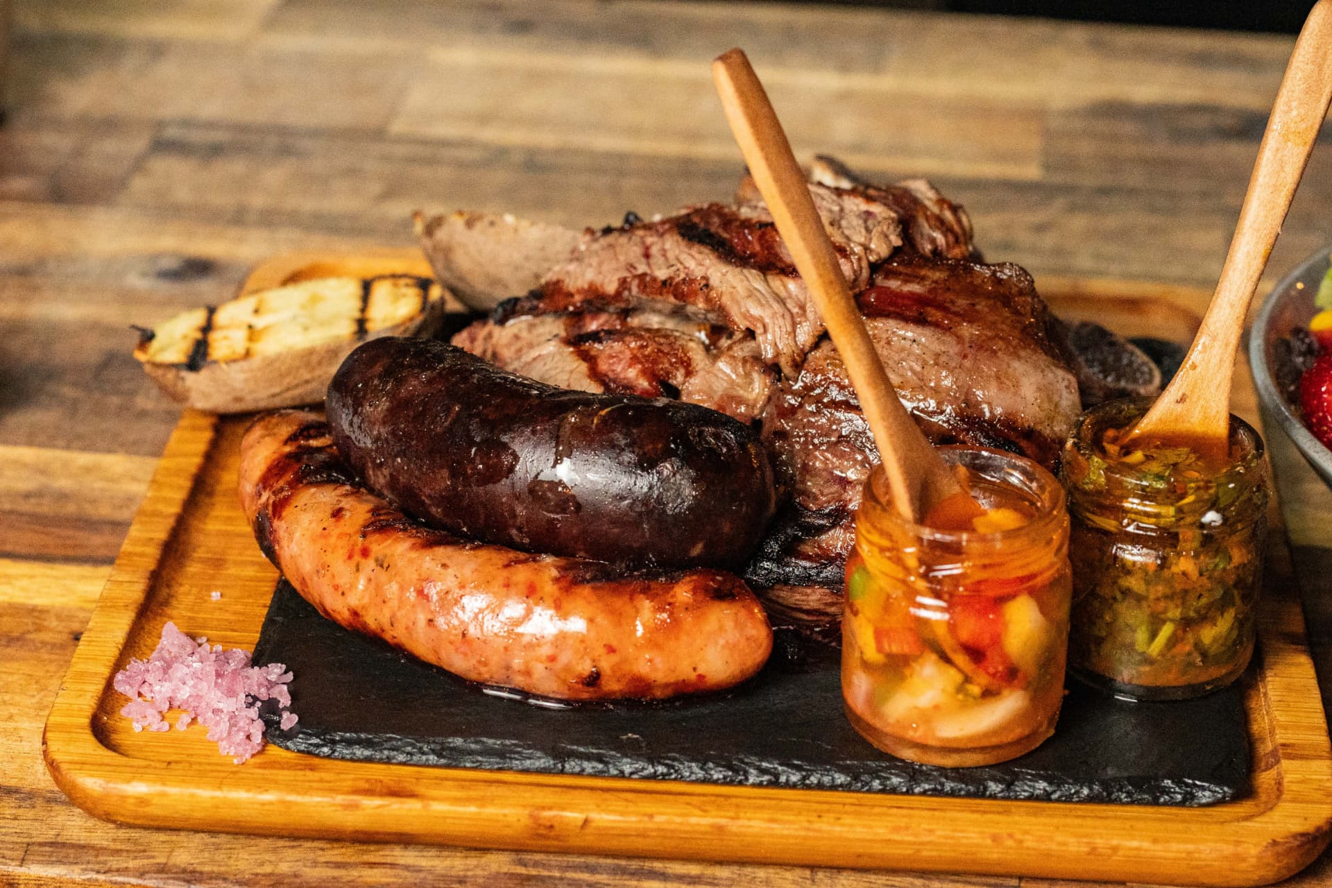 Parrillada board with grilled sausages, steaks and chimichurri